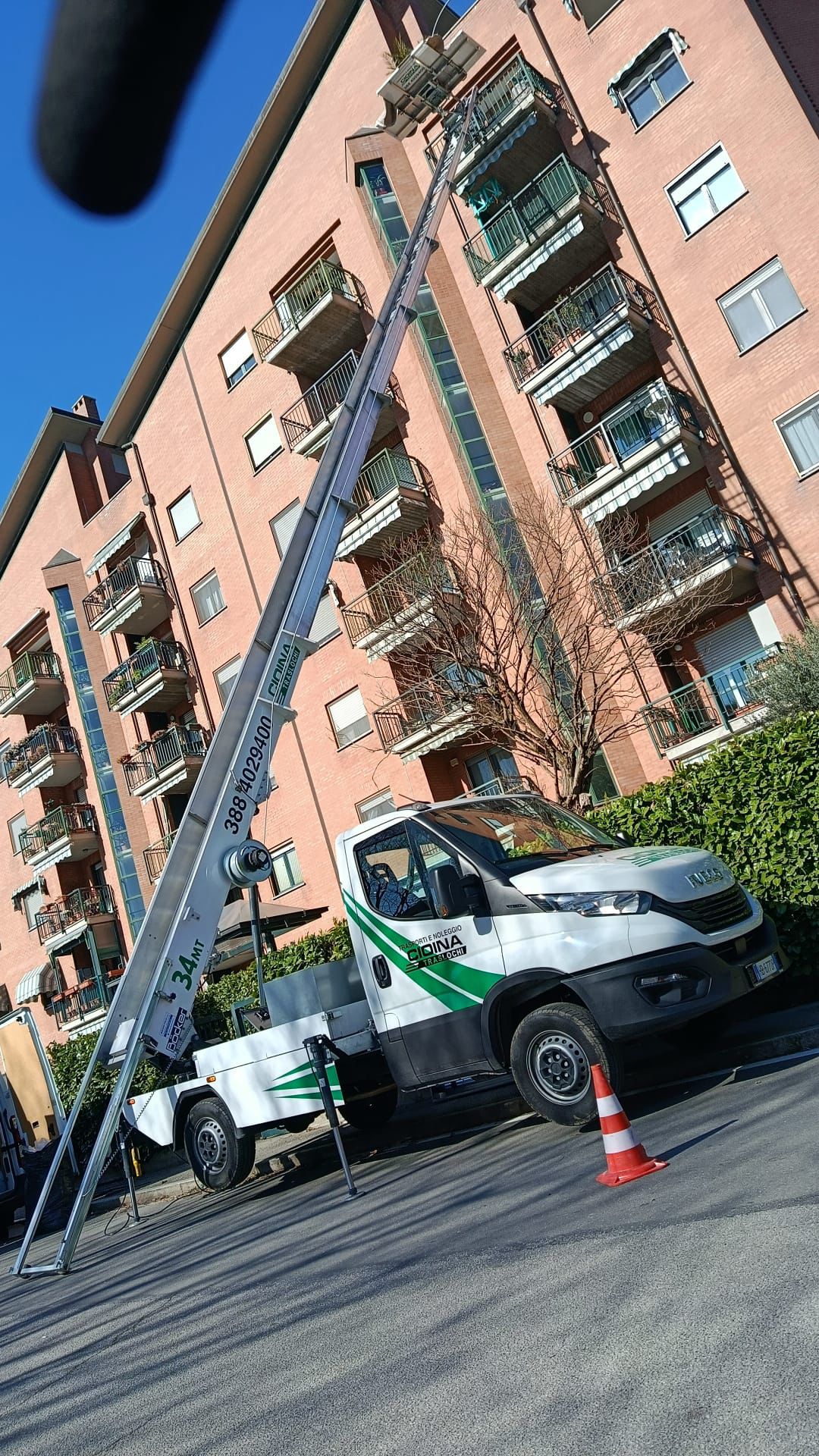 Autoscala da 34 metri con braccio esteso verso i piani alti di un condominio in mattoni