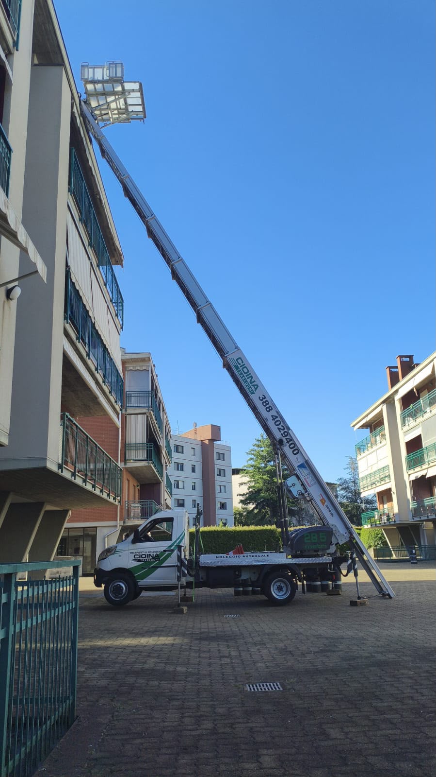 Autoscala con cestello estesa nel cortile pavimentato di un condominio, il caso più comune nei quartieri residenziali di Settimo