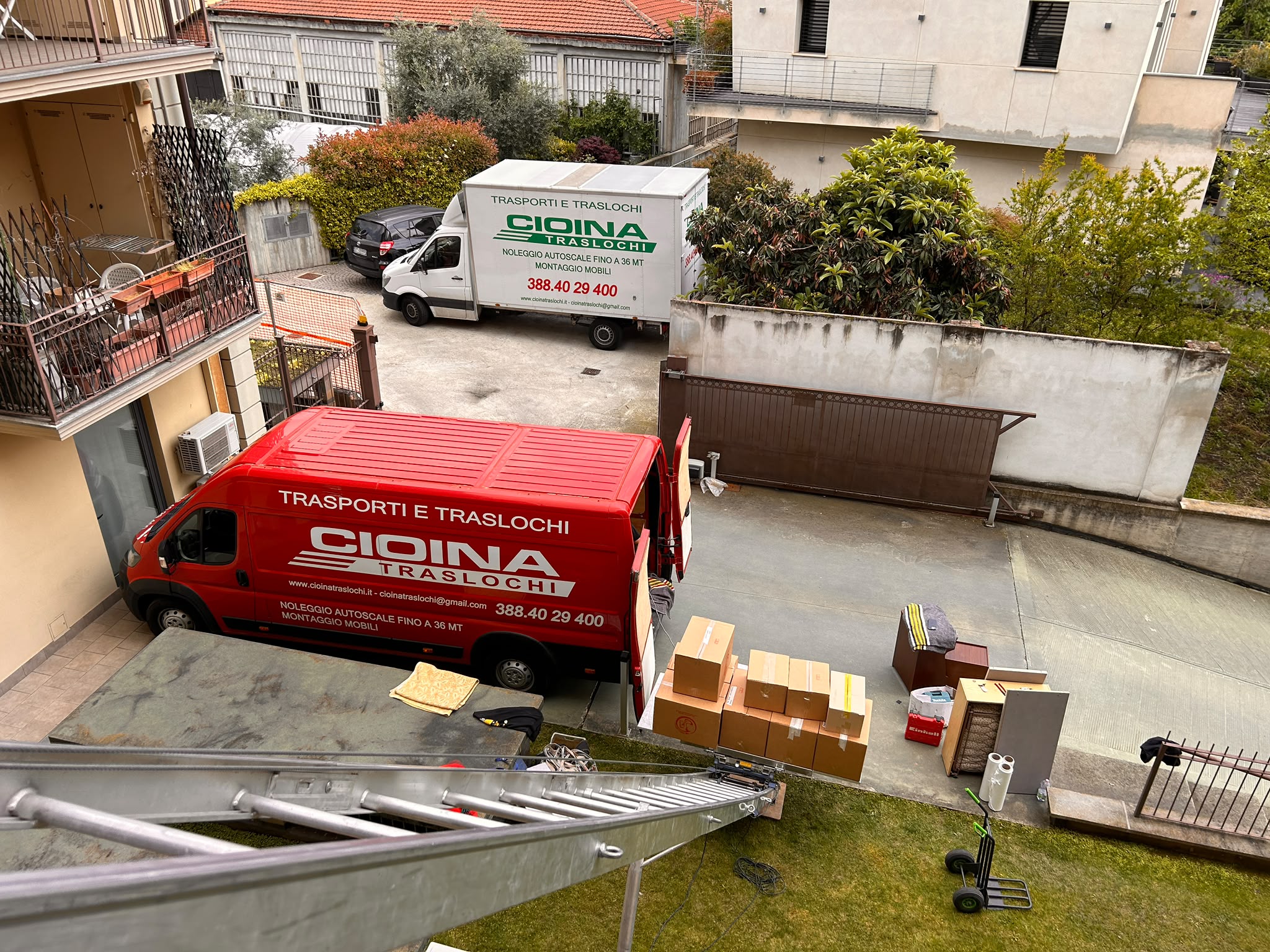 Sgombero in corso con scatoloni, carrello portapacchi e i mezzi Cioina nel cortile