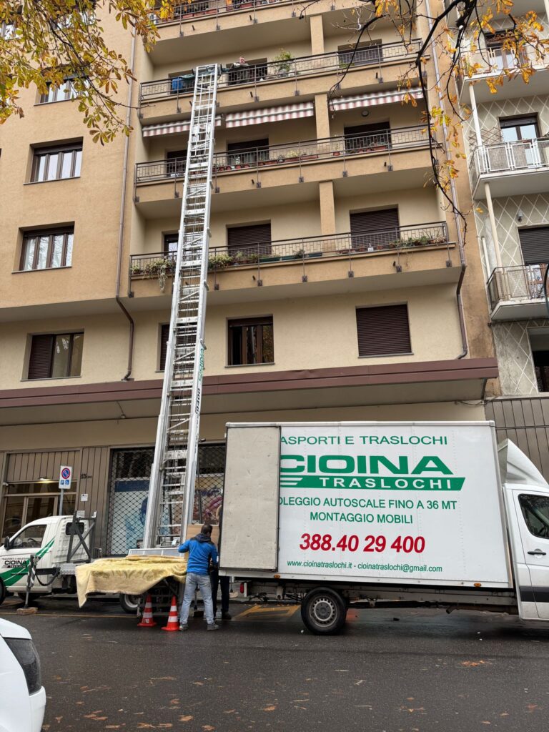 Due operatori Cioina Traslochi scaricano mobili dal camion in strada davanti a un palazzo