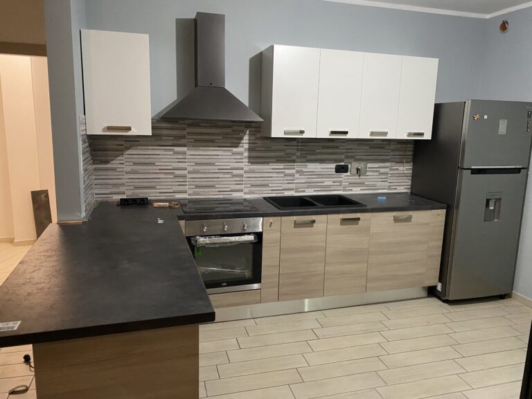 Cucina bianca con cappa in acciaio e piano scuro, rimontata e gia in uso dopo un trasloco